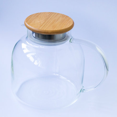 Stylish transparent tea pot with wooden lid on white backgroundの写真素材