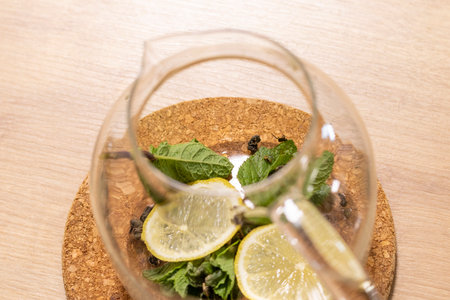 Stylish transparent tea pot with dried tea leaves, mint leaves and lemon slices in itの写真素材