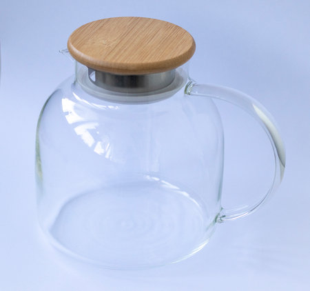 Stylish transparent tea pot with wooden lid on white backgroundの写真素材