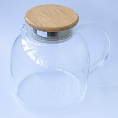 Stylish transparent tea pot with wooden lid on white backgroundの写真素材