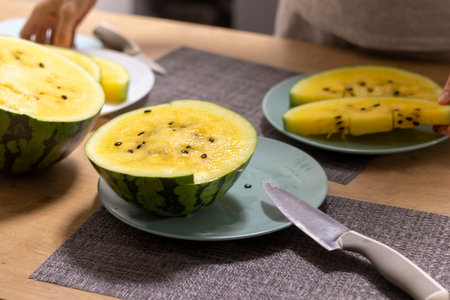 Close up shot of the cut watermelon with yellow flesh on ceramic plate.