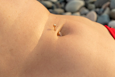 Close up shot of the flat woman belly with pierced bellybutton
