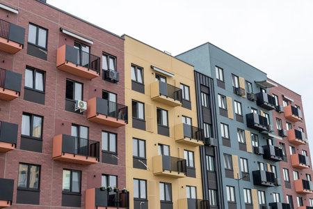 Modern residential building facade with geometric balconies, brick accent walls, and contemporary apartment block design.