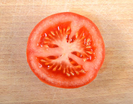 close-up of half tomato on wooden plateの写真素材