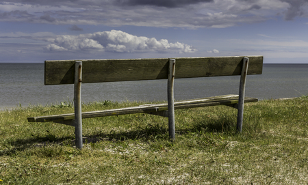 Old wooden bench on the beach with view over the seaの写真素材