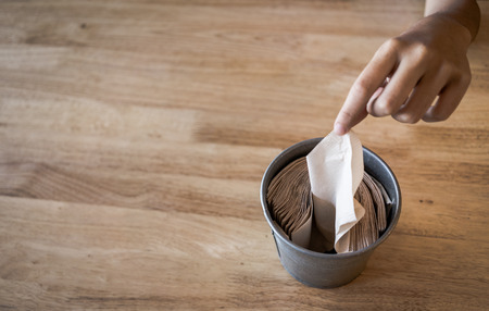 Hand pulling tissue paper, wooden table background, with copy space.