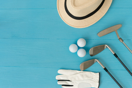 Golf concept : panama hat, glove, golf balls, golf clubs on wooden table. Flat lay with copy space.の写真素材