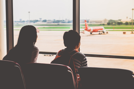 silhouette image of Asian girl and boy, waiting for departure at Airport.の写真素材