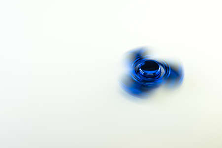 Spinning blue fidget spinner, on white background.
