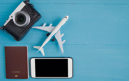 Travel Concept : Flat lay of vintage camera, smartphone, passport and plane model, on blue wooden background, with copy space.の写真素材