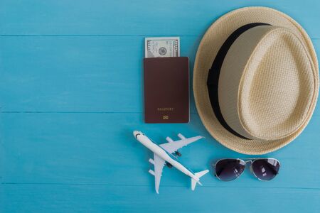 Travel Concept : Flat lay of straw hat, passport with money, plane model and sunglasses, on blue wooden background, with copy space.の写真素材