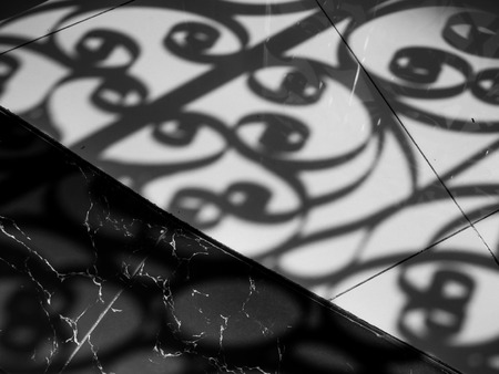 Shadow of curved steel window decoration shading on marble floor.の写真素材