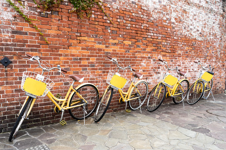 4 retro yellow bicycles parking by red brick wall. Bike sharing concept. Bike rental concept. Copy space on upper side.の写真素材
