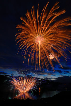Colorful fireworks of various colors over night sky and silhouette of peopleの写真素材