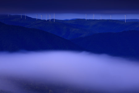 Foggy landscape with wind turbines in the middle of the mountainsの写真素材