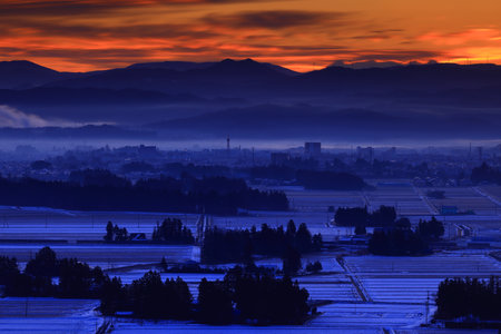 Sunset over a valley with fog and trees in the foregroundの写真素材