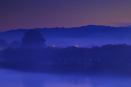 Sunset on the river, with fog and trees in the foregroundの写真素材