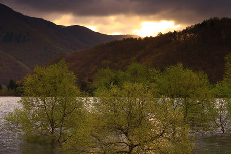 Sunset over a flooded lake with trees. Scenic view of a mountain landscape in the background.の写真素材