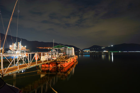 a night scene of a river in the moonlight with boat parked on the shoreの写真素材