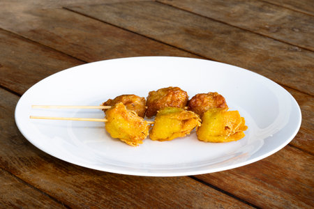 Close-up view of fried food on a white plate with stick on itの写真素材