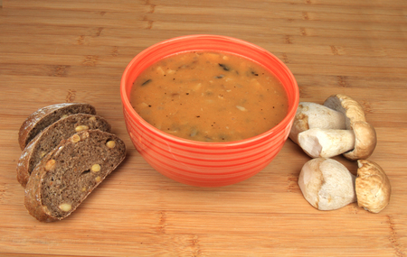 Goulash mushrooms in bowl on wooden table with fresh mushrooms sliced bread.の写真素材