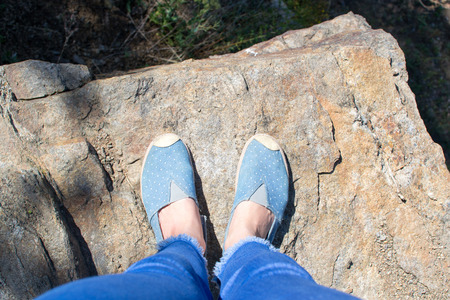 Top view female feet in jeans and sports shoes in public parkの写真素材