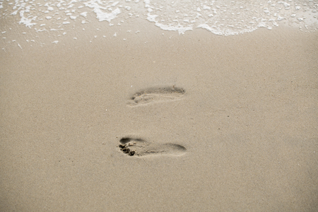 Footprints walking on the beach by the morningの写真素材