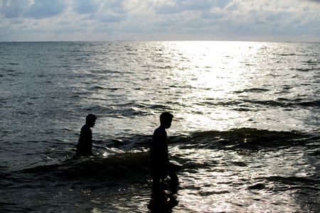 People walking on the beach at sunrise happily and the skies are a beautiful lightの写真素材