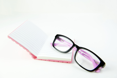 Black glasses and book orange on white background