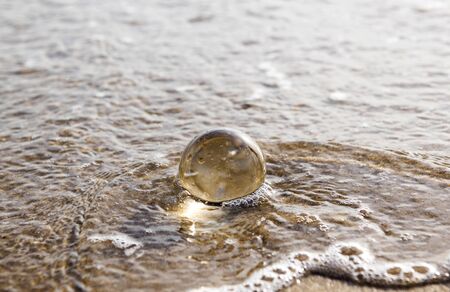 glass ball crystal clear reflecting the sea and beach in the morningの写真素材