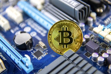 Golden Bitcoin token currency mining concept on a computer motherboardの写真素材