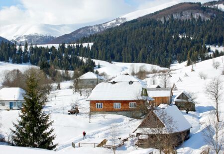 village in snowy winter snowdrifts in the mountains man with a child for a walkの写真素材