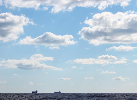 seascape blue sky and silhouettes of two ships on the horizon