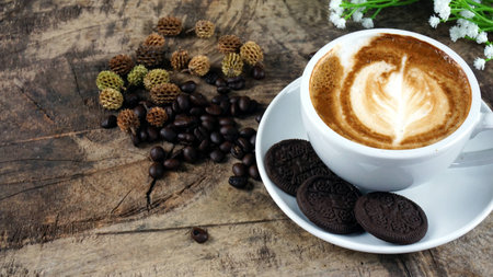 Cappuccino coffee. A cup of latte, cappuccino or espresso coffee with milk put on a wood table with dark roasting coffee beans. Drawing the foam milk on top.の写真素材