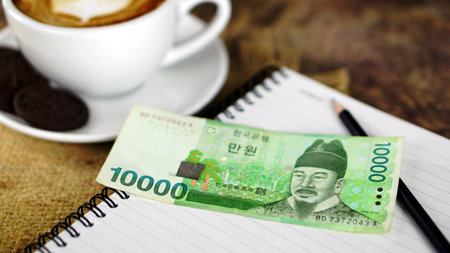 Cappuccino coffee and chocolate cookies. A cup of latte, cappuccino or espresso coffee with milk put on a wood table with dark roasting coffee beans and Won Korea bills.の写真素材