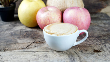 Cappuccino Coffee and fruits. A cup of latte, cappuccino or espresso coffee with milk put on a wood table with dark roasting coffee beans. Drawing the foam milk on top.の写真素材