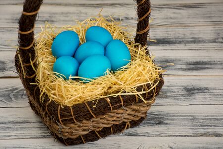 Blue easter egg in brown basketの写真素材