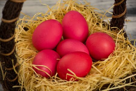 Red colored easter eggs in brown basketの写真素材