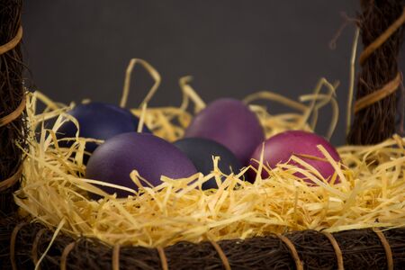 Purple colored easter eggs in brown basket