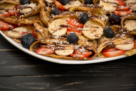 Homemade russian pancakes with banana, blueberries, strawberries and nutella.の写真素材