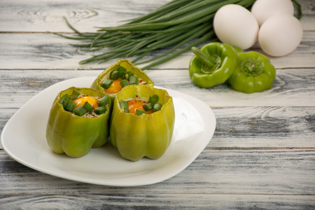 Eggs in green peppers with spices and green onionの写真素材