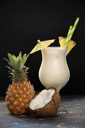 Cocktail pina colada, alcoholic beverage with straws, slice of pineapple and little cocktail umbrellaの写真素材