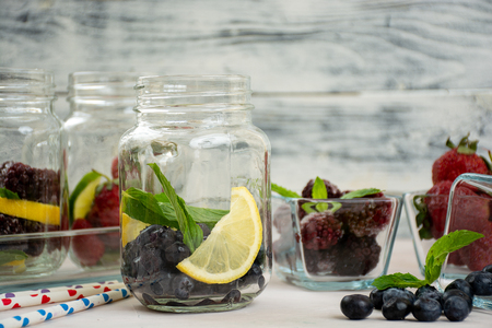 Refreshment drinks, water with frozen and fresh berries, lemons, limes and mint leavesの写真素材