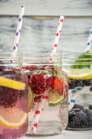 Refreshment drinks, water with frozen and fresh berries, lemons, limes and mint leavesの写真素材
