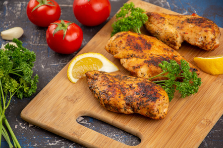 Grilled chicken breast on a wooden cutting boardの写真素材
