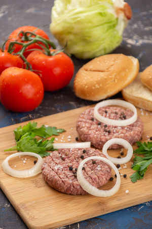Raw homemade minced beef burgers on wooden boardの写真素材