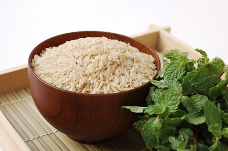 Raw brown rice in wooden bowl on white backgroundの写真素材