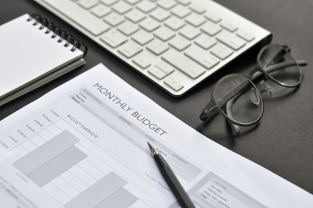 Balance sheet, eye glasses, blank notepad, and pencil on the tableの写真素材
