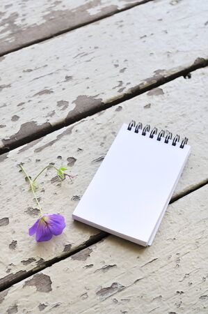 blank notepad and violet flower on rustic plank wood backgroundの写真素材
