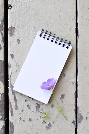 blank notepad and violet flower on rustic plank wood backgroundの写真素材